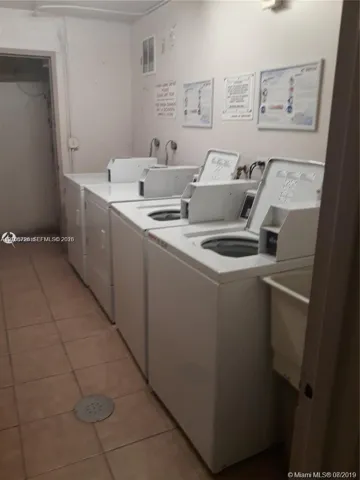 Laundry area featuring multiple top-loading washing machines and ceramic tile flooring