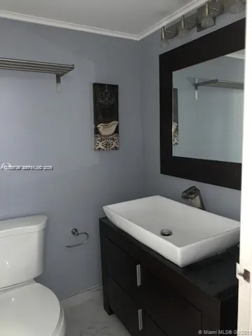 Dark wood-finish vanity featuring a white rectangular vessel sink, mounted mirror with a matching dark frame, and multi-bulb light fixture
