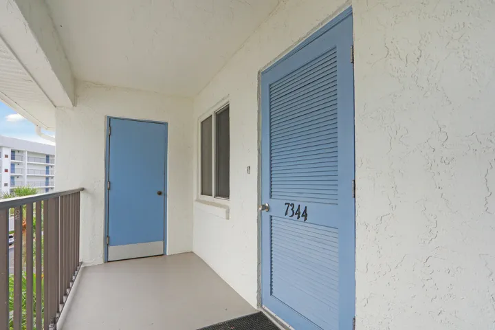 Entryway featuring a louvered door with unit number, a secondary solid door, and a window