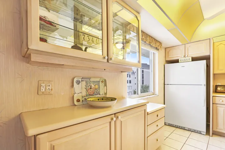 Kitchen featuring glass-front upper cabinetry, recessed lighting, solid surface countertops, light-toned lower cabinetry, and tile flooring