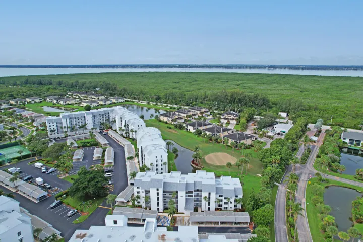 Aerial perspective showcasing multi-story residential buildings, water features, tennis courts, and a golf course green
