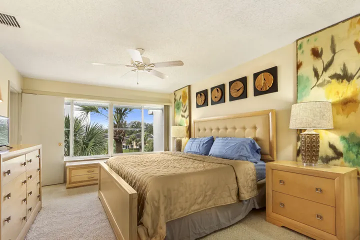 Spacious primary bedroom with wood-finish furnishings, upholstered headboard, and abundant natural light from expansive sliding glass doors