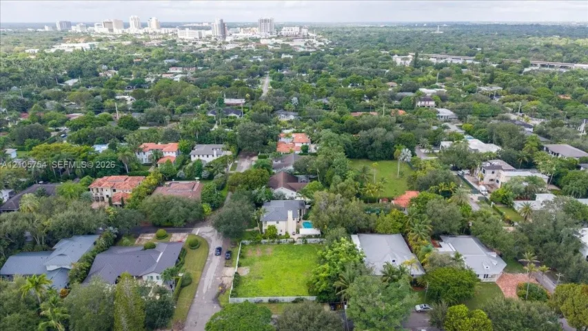 Aerial perspective of a corner lot situated in a tree-lined residential neighborhood with proximity to the urban skyline