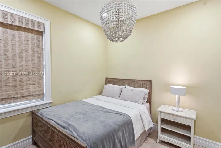 Beaded chandelier fixture, window with natural woven shade, and neutral wall paint