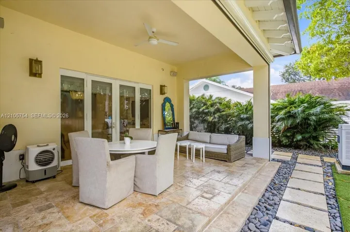 Covered patio featuring stone-tile flooring, recessed ceiling lighting, a mounted ceiling fan, and direct access through multi-panel glass doors