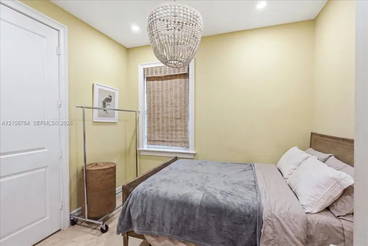 Textured bead chandelier, recessed ceiling lighting, and a window with a woven wood shade
