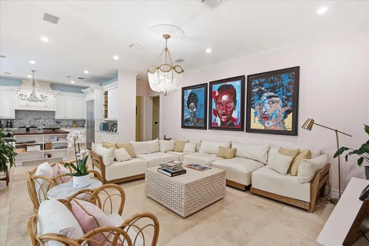 Open-concept interior featuring light stone flooring, recessed lighting, decorative ceiling medallion, and crystal chandelier fixture