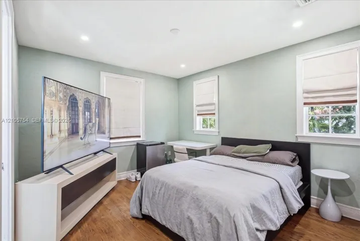 Room featuring wood-finish flooring, recessed lighting, and multiple windows with integrated window treatments