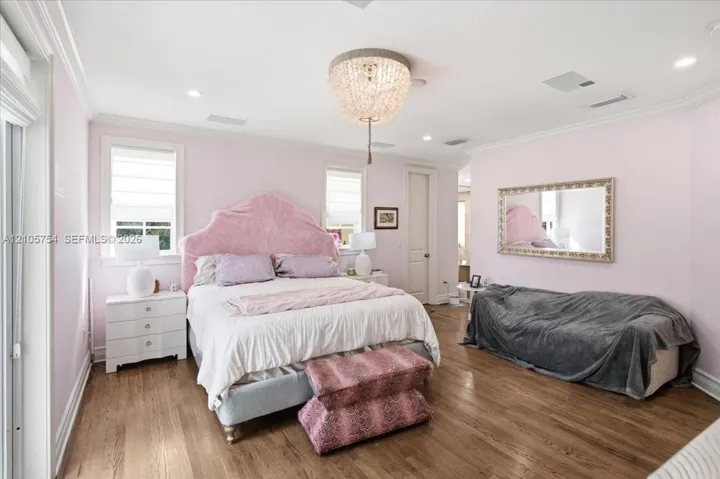 Interior space featuring wood-finish flooring, crown molding, recessed lighting, and a tiered crystal chandelier