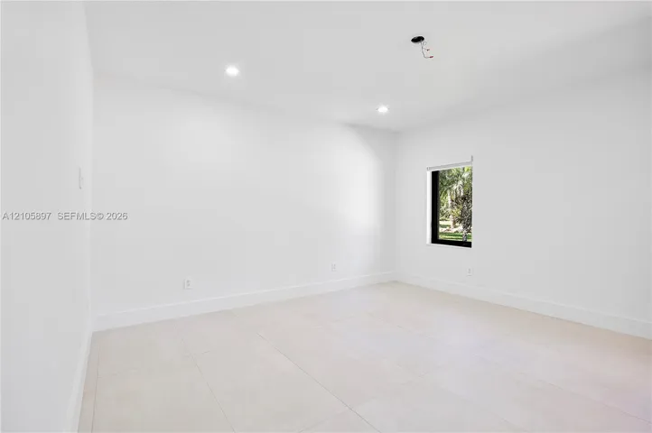Interior room featuring large-format tile flooring, recessed lighting, and a window with a dark frame