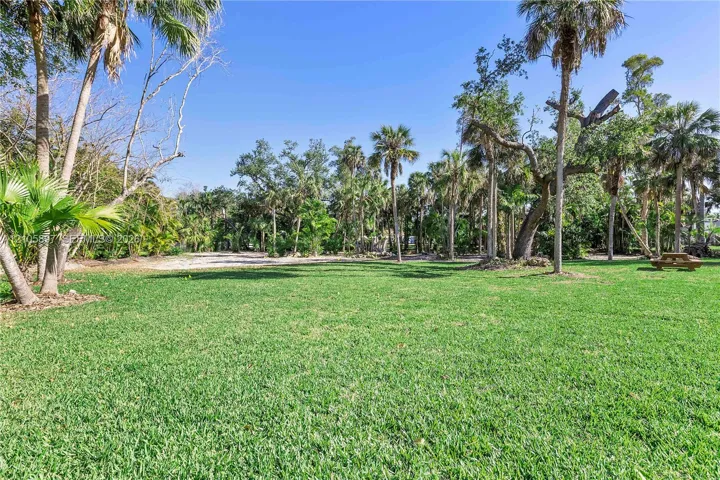 Expansive grounds featuring a manicured lawn, established palm trees, and mature native landscaping