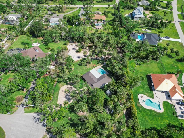 Aerial perspective featuring a residential lot with mature landscaping, extensive tree coverage, and a private swimming pool