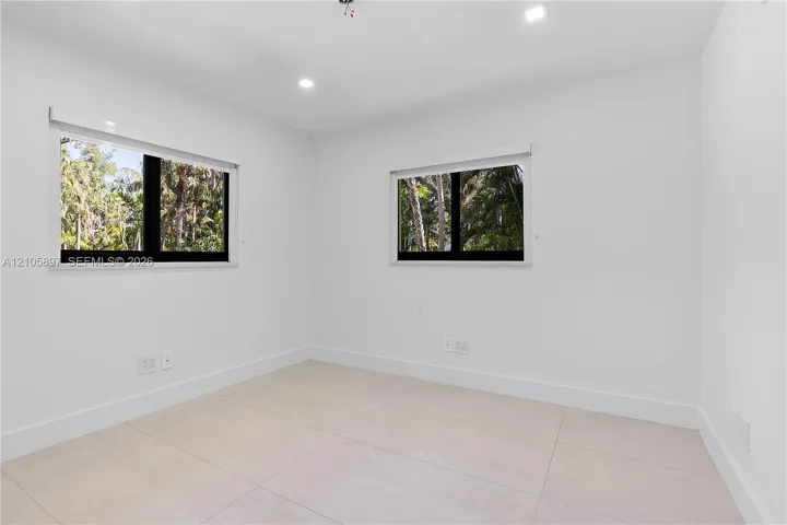 Neutral-toned large-format tile flooring, recessed ceiling lighting, and dual windows with black frames