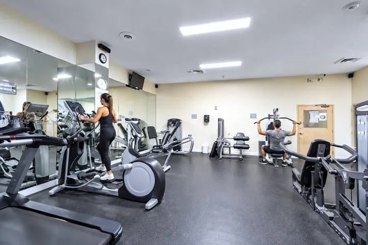 Fitness center featuring wall-to-wall mirrors, recessed lighting, and resilient rubber flooring