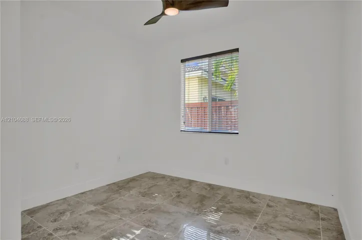 Interior space featuring large-format stone-finish flooring, a ceiling fan with integrated lighting, and a window with horizontal blinds