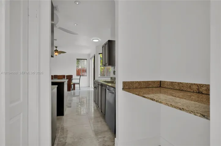 Kitchen featuring dark cabinetry, stone-surface counters, high-gloss tile flooring, and integrated ceiling lighting