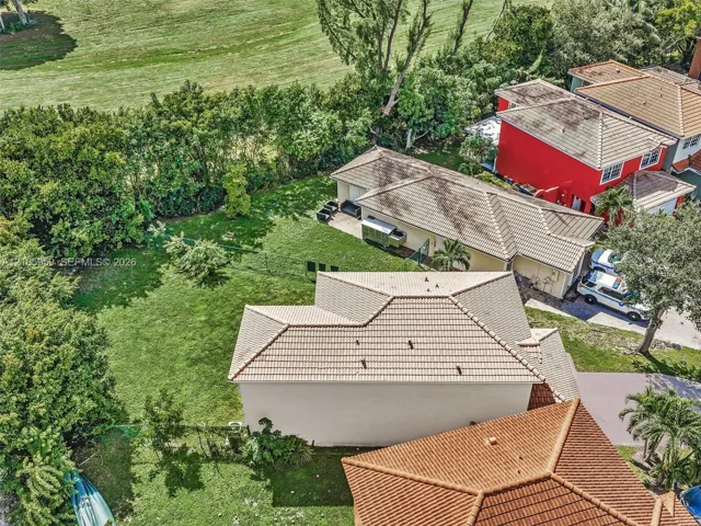 Expansive backyard featuring a manicured lawn, concrete patio, and tile roof structures