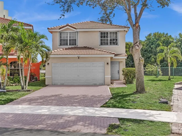 Two-story residence featuring a stucco exterior, clay tile roof, attached garage, and paved driveway
