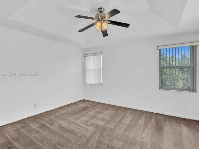 Tray ceiling featuring a brushed nickel multi-blade ceiling fan with integrated lighting and wall-to-wall carpeting