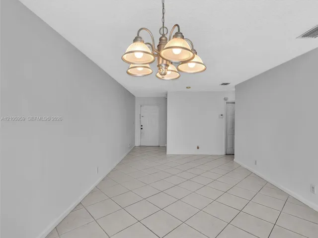 Interior space featuring neutral wall paint, diagonal-set ceramic tile flooring, and a multi-arm chandelier with frosted glass shades