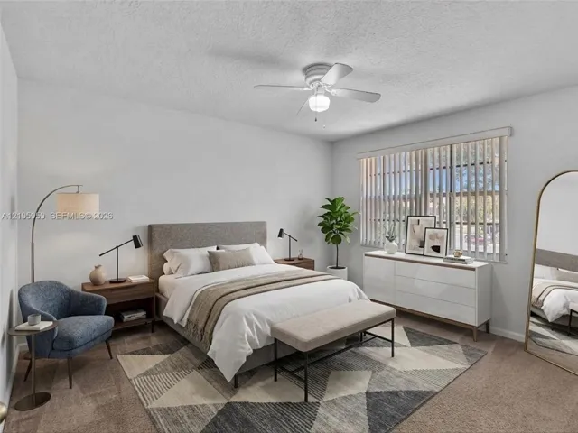Spacious room featuring neutral carpeting, a white-finished ceiling fan with light fixture, and vertical window blinds