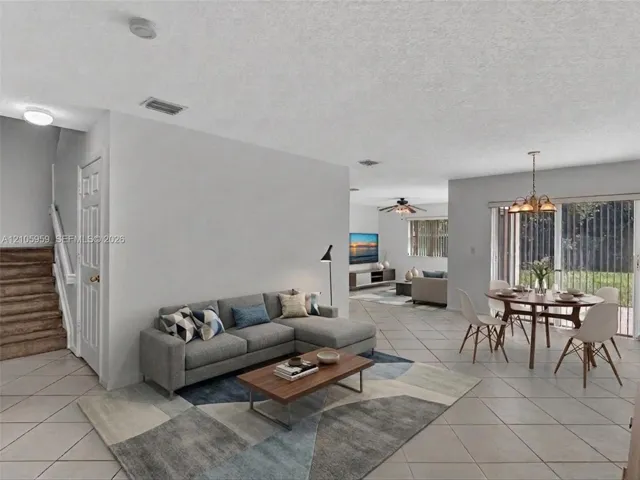 Open-concept interior featuring light-toned tile flooring, recessed lighting, a multi-light chandelier, and sliding glass doors