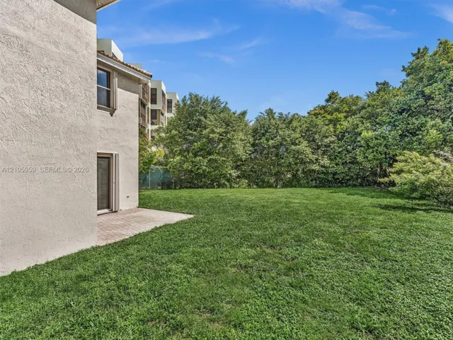 Stucco exterior finish with paver patio, expansive green space, and mature perimeter trees