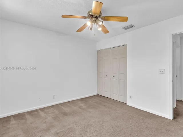 Interior space featuring neutral wall tones, wall-to-wall carpeting, bi-fold closet doors, and a ceiling fan with integrated lighting