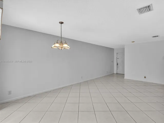 Open-concept interior featuring neutral wall tones, large-format tile flooring set on a diagonal, and a multi-arm polished metal chandelier