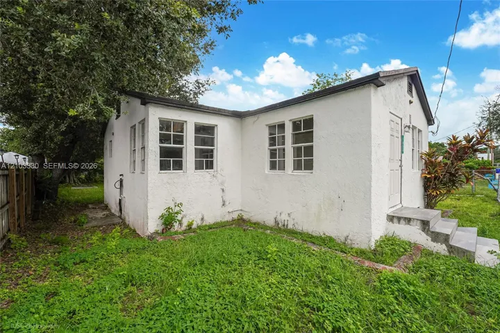 Stucco exterior featuring a gabled roofline, multi-pane windows, and concrete front entry steps