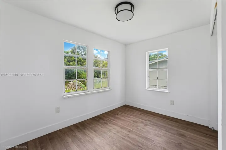 Interior space featuring wood-finish flooring, multi-pane windows, and a circular flush-mount ceiling light fixture