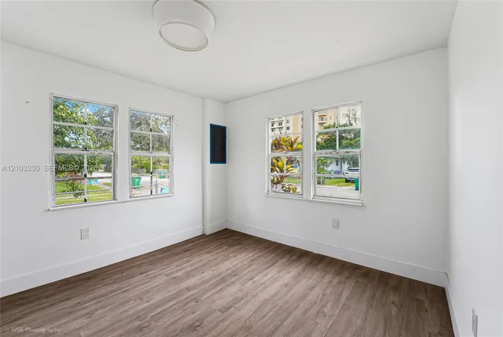 Neutral interior featuring wood-finish flooring, four multi-pane windows, and a circular flush-mount ceiling fixture
