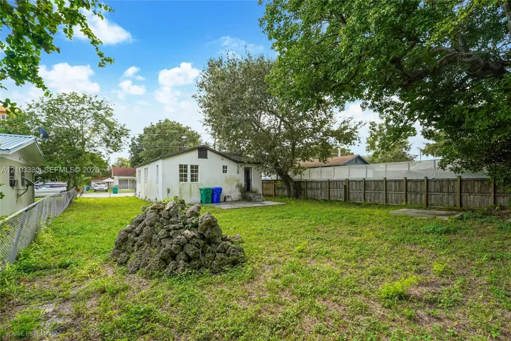 Expansive backyard featuring a lawn, mature trees, and a wooden privacy fence