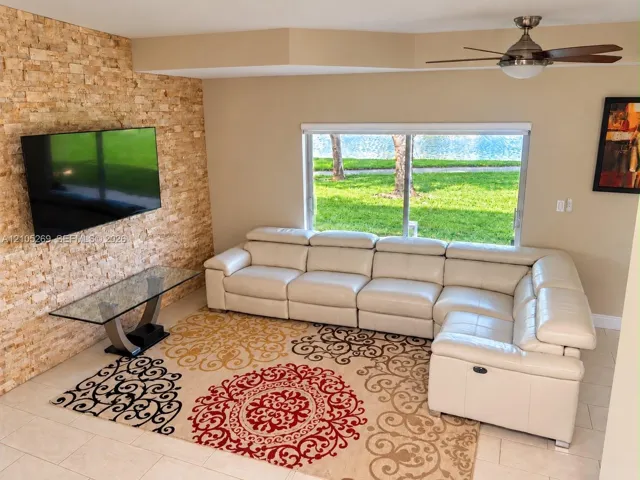 Stone accent wall, large window, ceiling fan, and tiled flooring