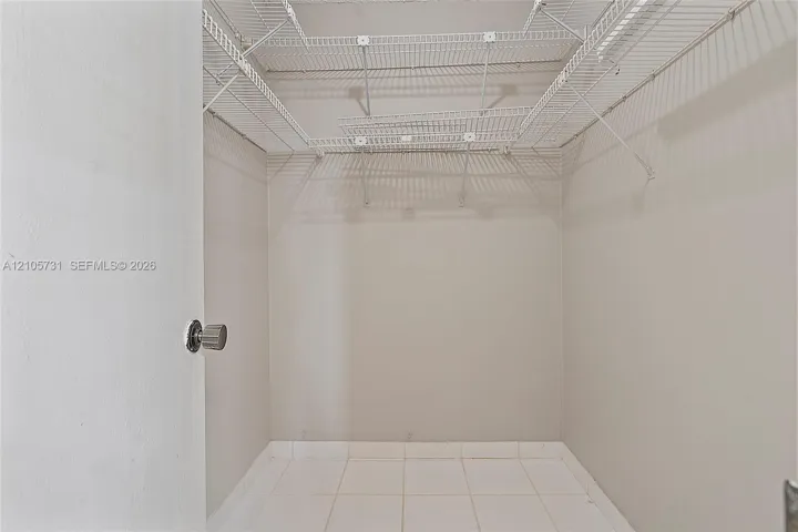 Storage area featuring white wire shelving and tile flooring