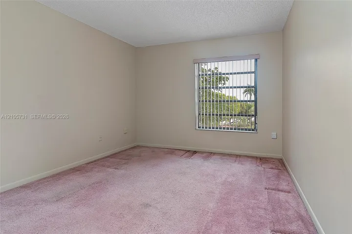 Interior room featuring neutral wall paint, wall-to-wall carpeting, and a window with vertical blinds