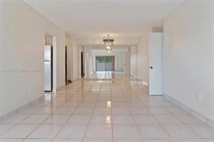 Neutral tile flooring, expansive mirrored wall panels, and a tiered crystal chandelier