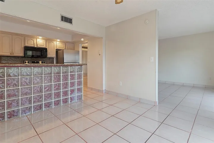 Kitchen featuring a glass block peninsula, stone-surfaced countertops, custom cabinetry, and ceramic tile flooring