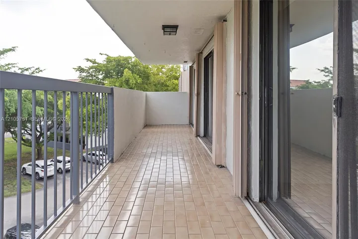 Covered balcony featuring tile flooring, metal railing, and sliding glass door access