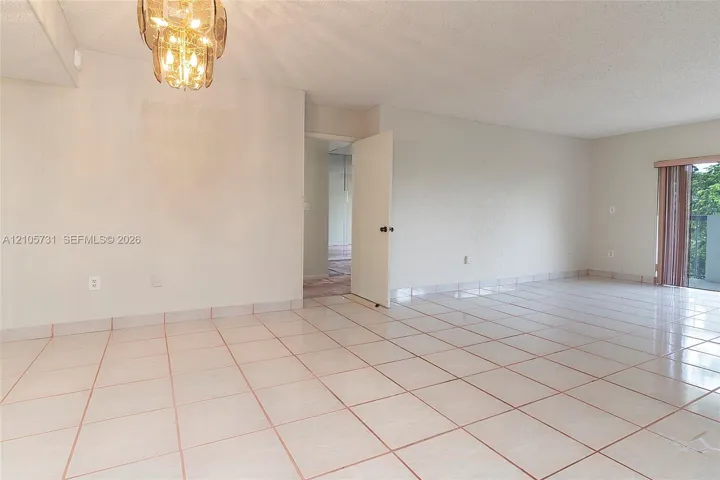 Large format tile flooring, metallic multi-light chandelier, and full-height glass door panel