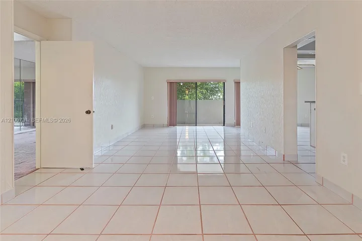 Open floor plan featuring ceramic tile flooring, textured ceilings, and a sliding glass door providing external access