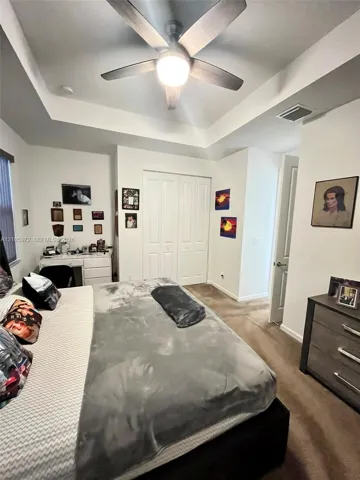Tray ceiling featuring a central multi-blade ceiling fan with integrated lighting and double-door closet cabinetry