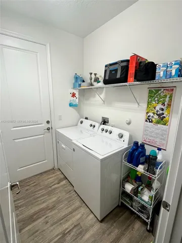 Laundry area featuring wood-finish flooring, a solid-core interior door, and overhead wire shelving