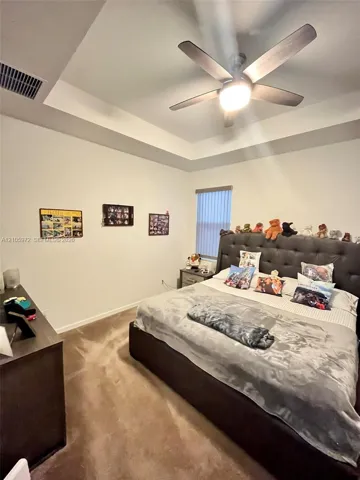 Tray ceiling featuring a central five-blade ceiling fan with integrated lighting and carpeted flooring