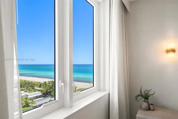 Floor-to-ceiling windows, dual-sconce wall lighting, and expansive coastal horizon