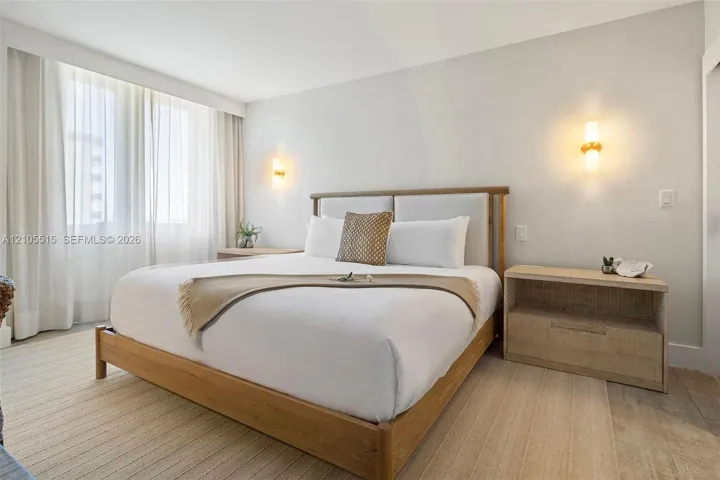 Neutral color palette, wall-to-wall carpeting, expansive windows with floor-to-ceiling drapery, and dual wall-mounted light fixtures