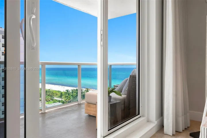 Private balcony with glass railing, sliding glass door entry, and panoramic ocean backdrop