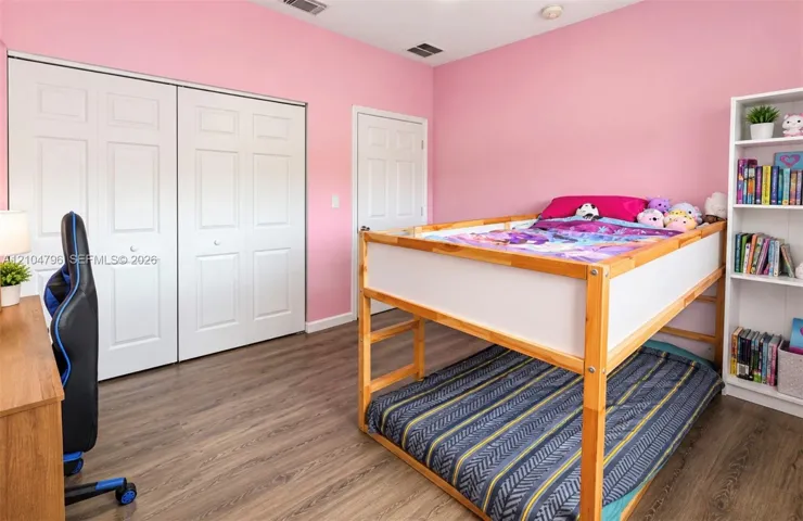 Room featuring wood-finish flooring, dual-panel closet doors, a traditional interior door, and white millwork