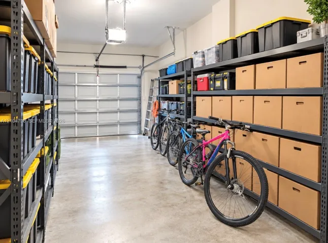 Garage space featuring finished concrete flooring, a sectional overhead garage door, and extensive industrial-style metal storage shelving
