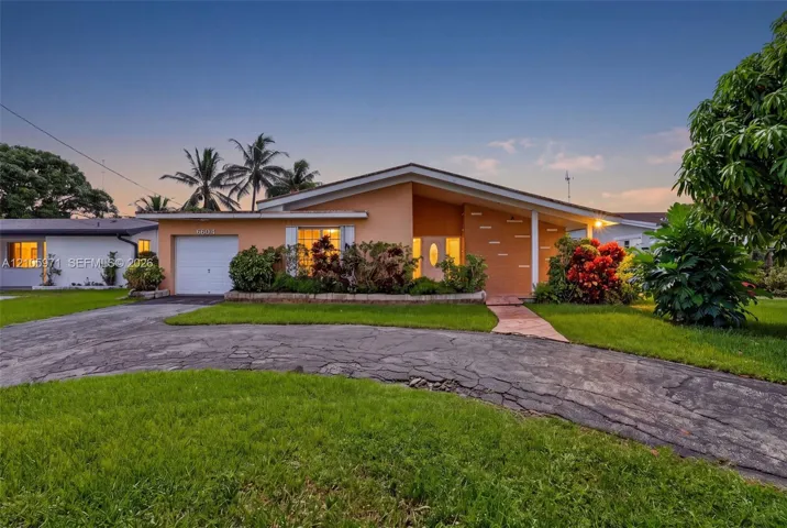 Mid-century modern architectural style featuring a low-pitch roofline, integrated single-car garage, stone masonry accents, and a winding driveway